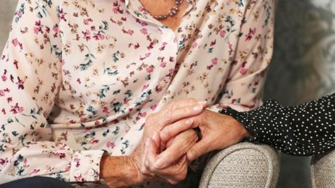 Care home resident holding hands with daughter