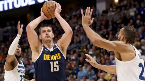 Nikola Jokic #15 of the Denver Nuggets goes to the basket against Monte Morris #23 and Rudy Gobert #27 of the Minnesota Timberwolves