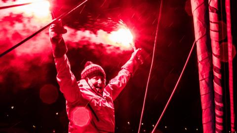Pip Hare lets off flares after reaching the finish of the Vendee Globe