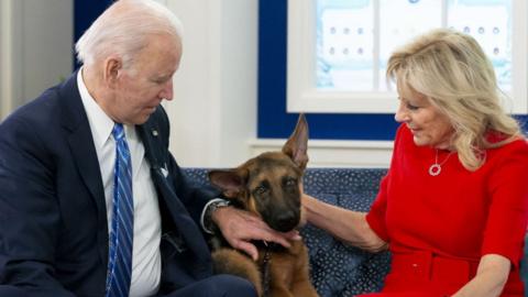 U.S. President Joe Biden, left, and First Lady Jill Biden pet their German Shepherd "Commander" while meeting virtually with United States service members serving around the world in the Eisenhower Executive Office Building in Washington, D.C., U.S., on Dec. 25, 2021.