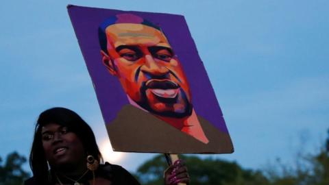 Woman holds a poster of George Floyd at a rally in Brooklyn, NY 25 May 2021