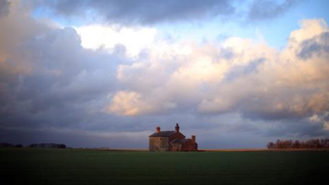 A derelict farm house adorns the horizon