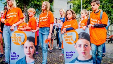 Children hold placards that say Howick and Lily belong in the Netherlands