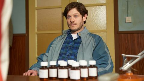 Iwan Rheon in the new BBC series Men Up, pictured sitting at a table in front of pill bottles