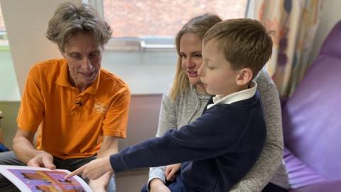 Michael Loader reading a book to a young boy