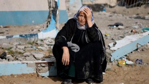 A woman sits next to a destroyed building in Rafah, southern Gaza. Photo: February 2024