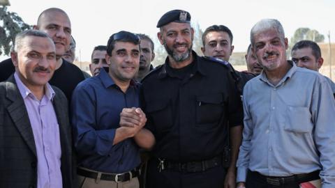 A member of the Palestinian Authority (C-L) shakes hands with Hamas security men at the Rafah border crossing with Egypt (1 November 2017)