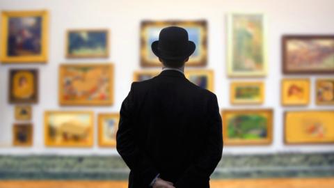 A man in a bowler hat surveys a gallery wall with his hands behind his back