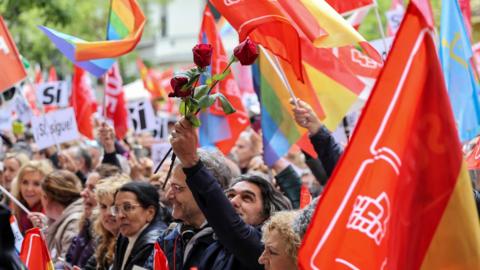 A man holds a rose as people gather outside Spain's Socialist Party headquarters to show support for the Prime Minister Pedro Sanchez in Madrid