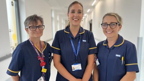 Three nurses in uniform, smiling