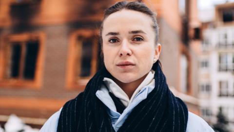 Elina Svitolina poses outside a damaged building