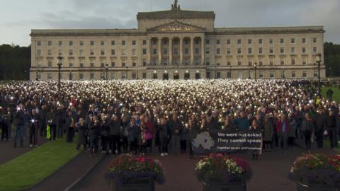Protesters stand in front of Stormont shining torches