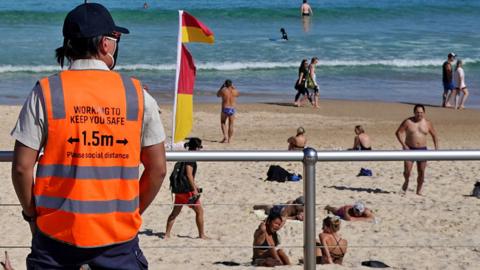 A Covid-19 social distancing marshal from Waverley Council watches over beachgoers at Bondi Beach during a lockdown in Sydney, Australia, on 1 September 2021