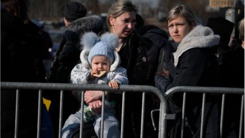 People waiting to board buses after crossing from Ukraine into Poland