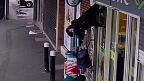 CCTV captures the moment a woman is hoisted into the air by shop shutters