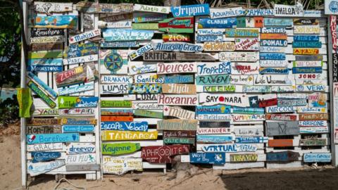 A wall of painted names and locations at a beach restaurant on Carriacou, Grenada.