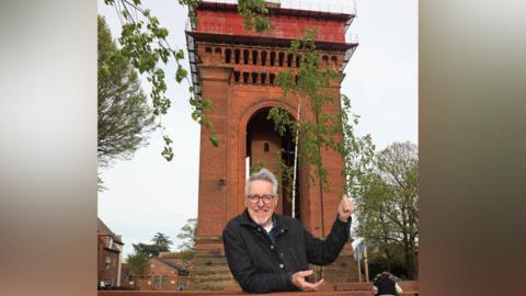 Griff Rhys Jones standing in front of the Jumbo Tower in Colchester