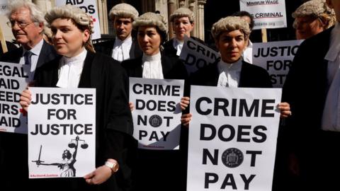 Lawyers hold placards outside the Royal Courts of Justice, in London