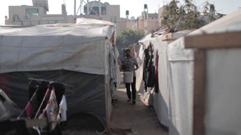 Man stands near tents at UNRWA training college in Khan Younis