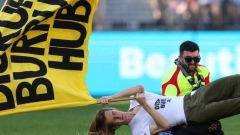 A protester is tackled to the ground after storming an Australian Rules Football match in Perth on 20 May