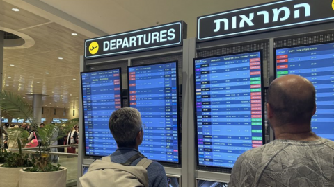 People examine departure board at Ben Gurion Airport