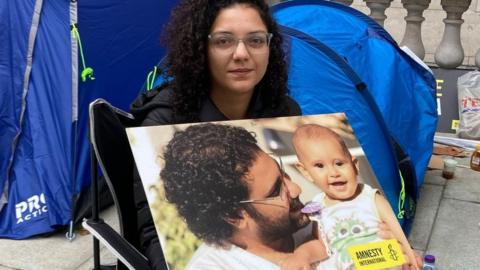 Sanaa Seif holds a photo of her brother Alaa Abdel Fattah and his son at a sit-in protest outside the Foreign, Commonwealth and Development Office in London, UK (1 November 2022)