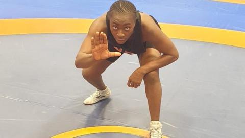 Madusu Koroma squats in wrestling pose in ring