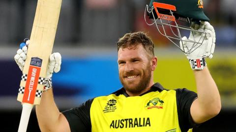 Former Australia captain Aaron Finch raises his bat and helmet to celebrate a T20 victory