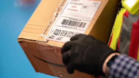 An employee explains the tracking codes on a test package at the Amazon AGS5 sort facility on October 27, 2022 in Appling, Georgia.