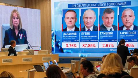 International observers sit in front of a screen showing preliminary results of the presidential elections at the Central Election Commission in Moscow, Russia