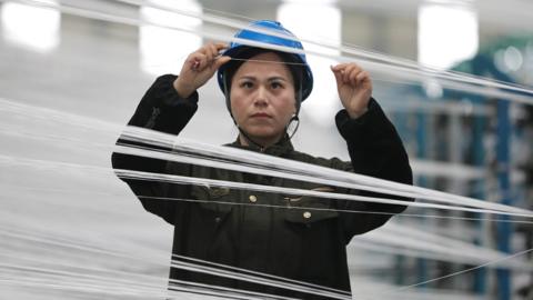 An female employee works on a production line at a workshop of a textile factory in China