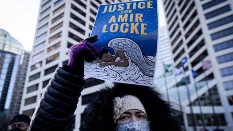 A demonstrator holds a "Justice for Amir Locke" sign during a rally in protest of the killing of Amir Locke, outside the Hennepin County Government Center in Minneapolis, Minnesota on February 5, 2022.