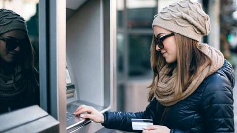 Young woman uses ATM machine