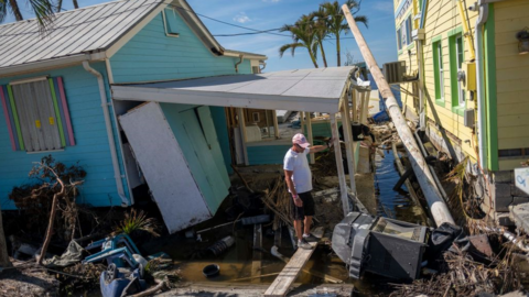 Man surrounded by debris and houses damaged after hurricane Ian hit