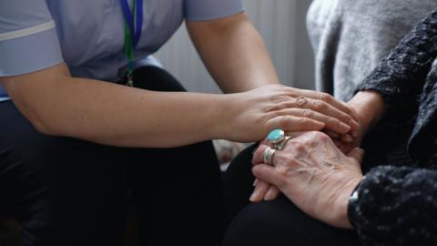 A care worker holding a patient's hand