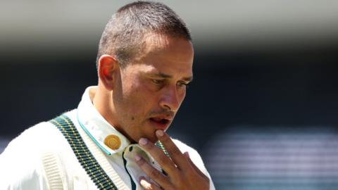 Australia opener Usman Khawaja holds his chin after being hit by a bouncer from West Indies' Shamar Joseph