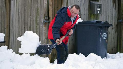 Man shovelling snow in Cumbria