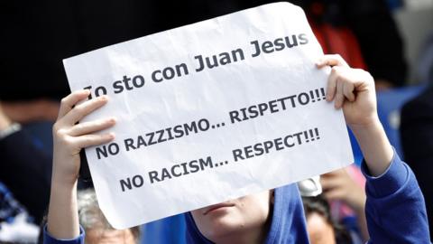 Fans display anti-racism banners within the Diego Maradona stadium