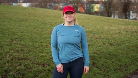 Image of Maria Mcmenemy. She is outside on a run in Bristol. In the picture, she is stood up, looking directly at the camera and smiling.