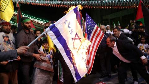 Protesters burn the Israeli and US flags at a anti-Israel demonstration in Tehran, Iran (1 April 2024)