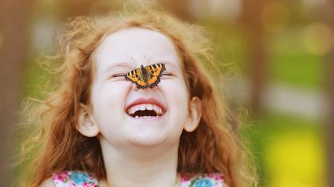 Child smiling with butterfly on her nose