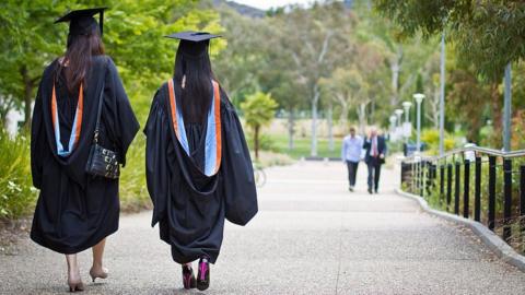 Chinese students in graduation robes walk away with their backs turned at the Australian National University