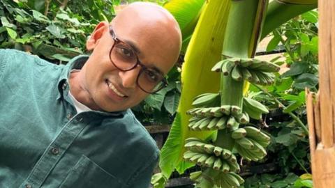 Ripon Ray stands next to his banana plant