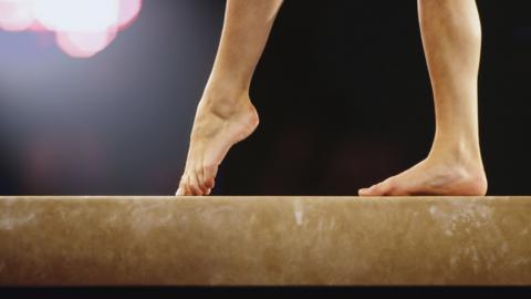 Female gymnast walking on balance beam