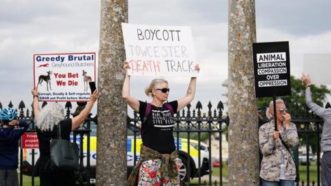 Protesters holding up placards including Boycott Towcester Death Track outside Towcester racecourse
