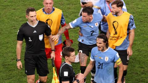 Uruguay players remonstrate with the referee and assistant referee after their win over Ghana