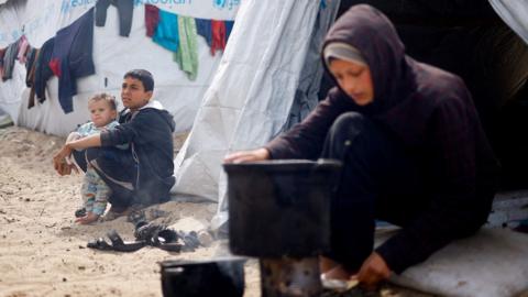 Displaced Palestinian children sit outside tents at a camp in Rafah, in the southern Gaza Strip (6 March 2024)