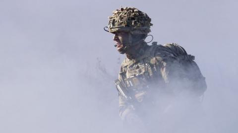 A soldier of the United Kingdom's 2nd Battalion Royal Anglian infantry unit runs through smoke