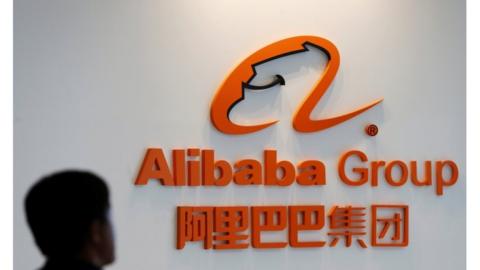 A man stands near the logo of Alibaba Group at the company"s newly-launched office in Kuala Lumpur