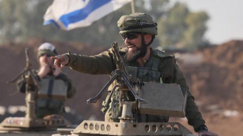 An Israeli soldier stands atop a tank near the boundary with Gaza